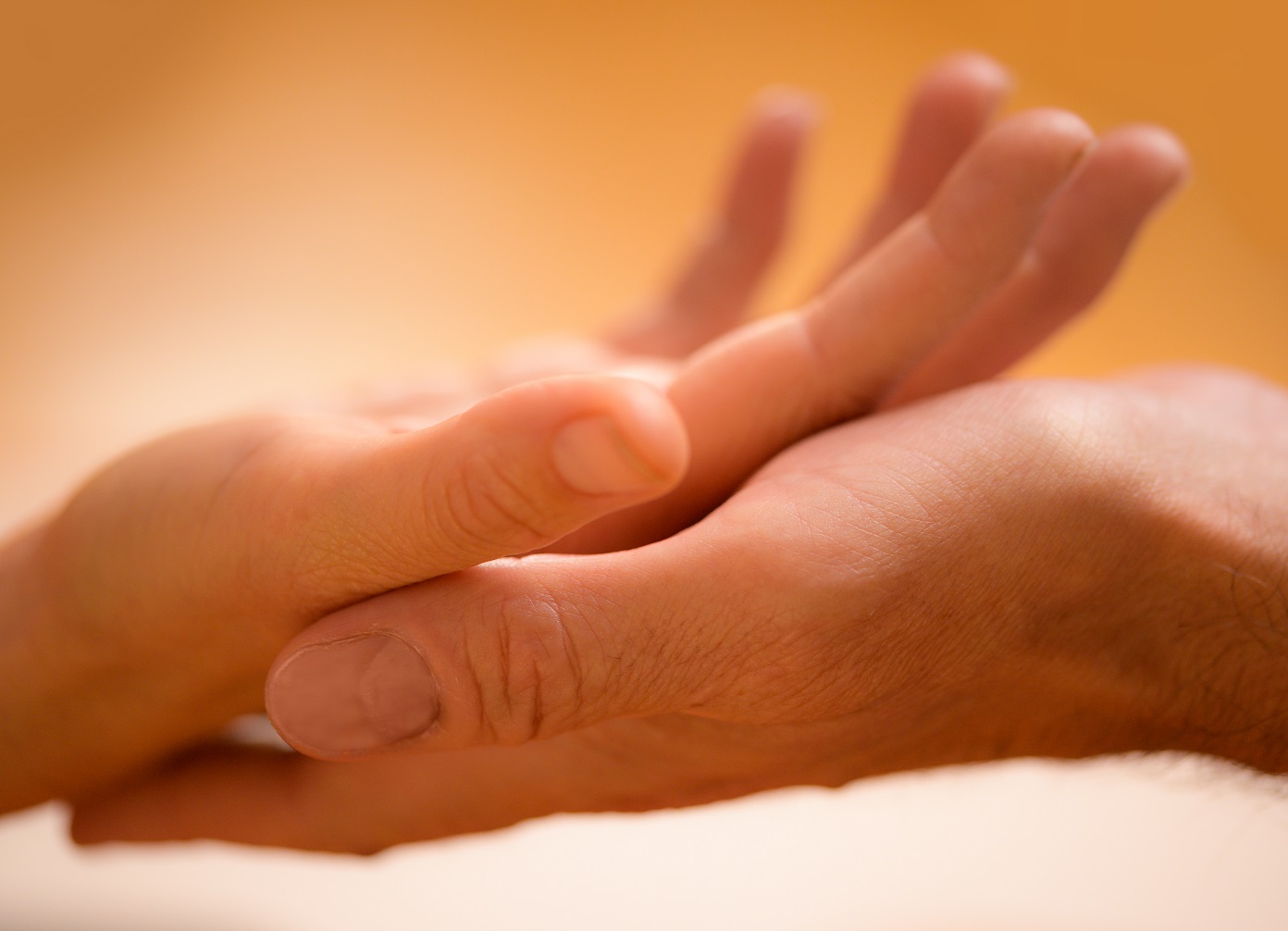 Eine kleinere Hand in einer größeren, zart und liebevoll mit lachsfarbenem Hintergrund